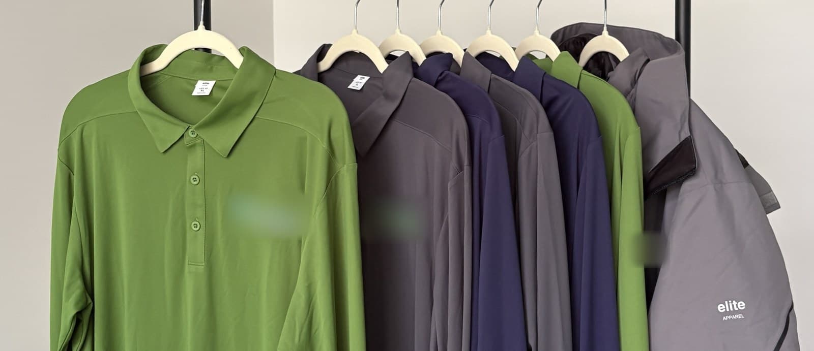 Long-sleeve polos in green, grey, and navy with a grey shell jacket on a rack, logos covered
