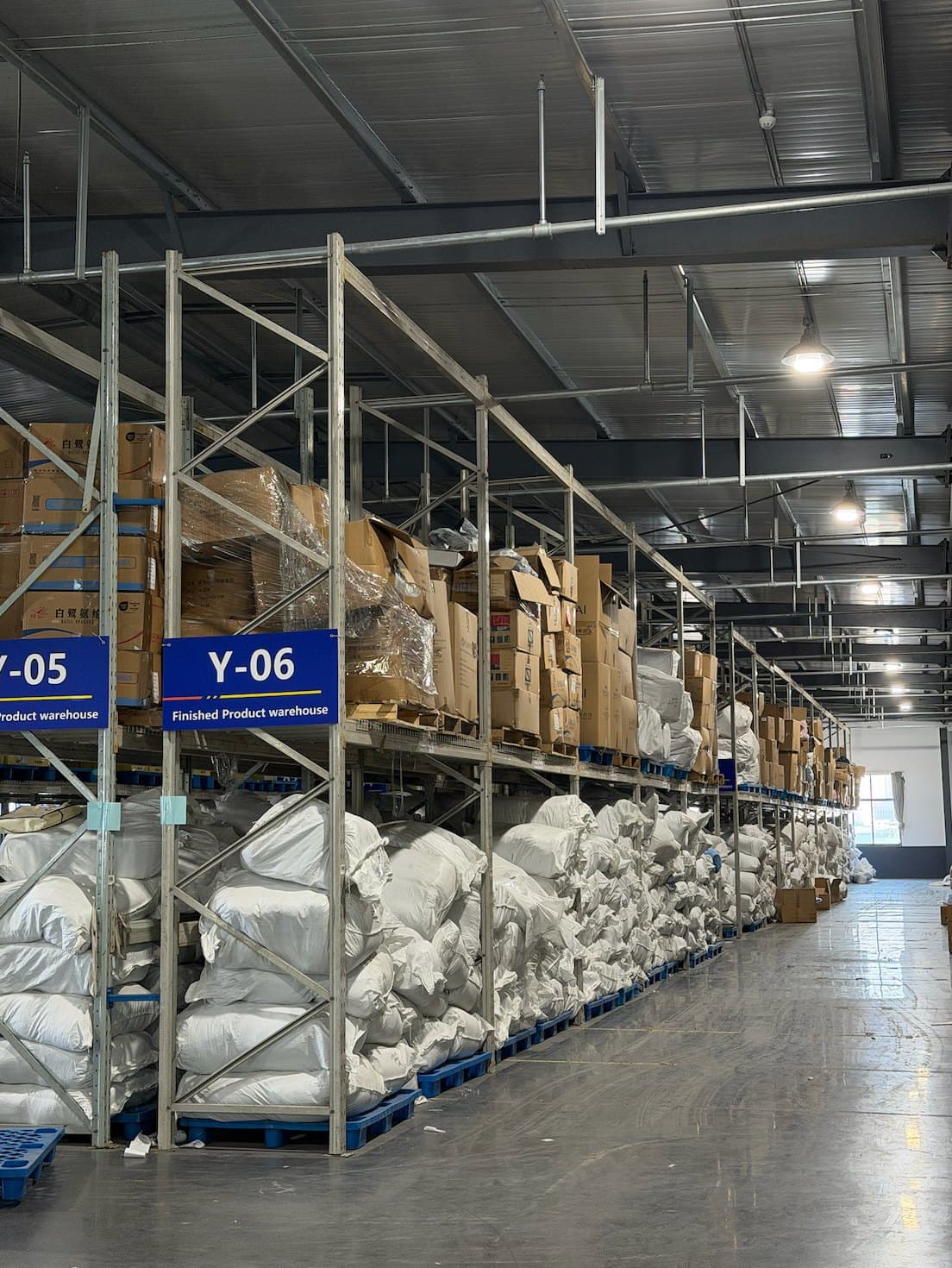 Finished-goods warehouse lined with inventory racks — multi-product programs consolidated for delivery