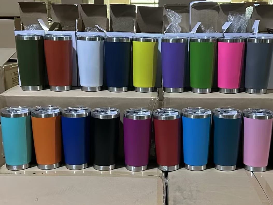 Nineteen insulated tumblers in a full color range, lined up on cartons at the factory